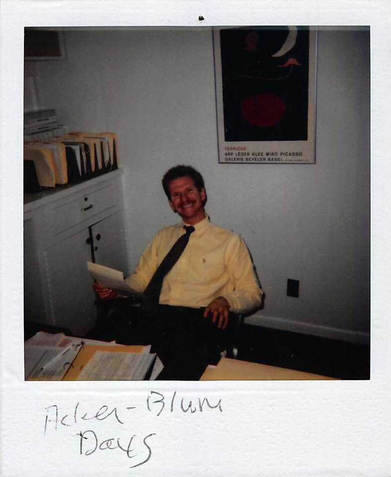 Mike Spear at his desk during his Acker-Blum years, in a yellow shirt and tie beside a wall of paper files